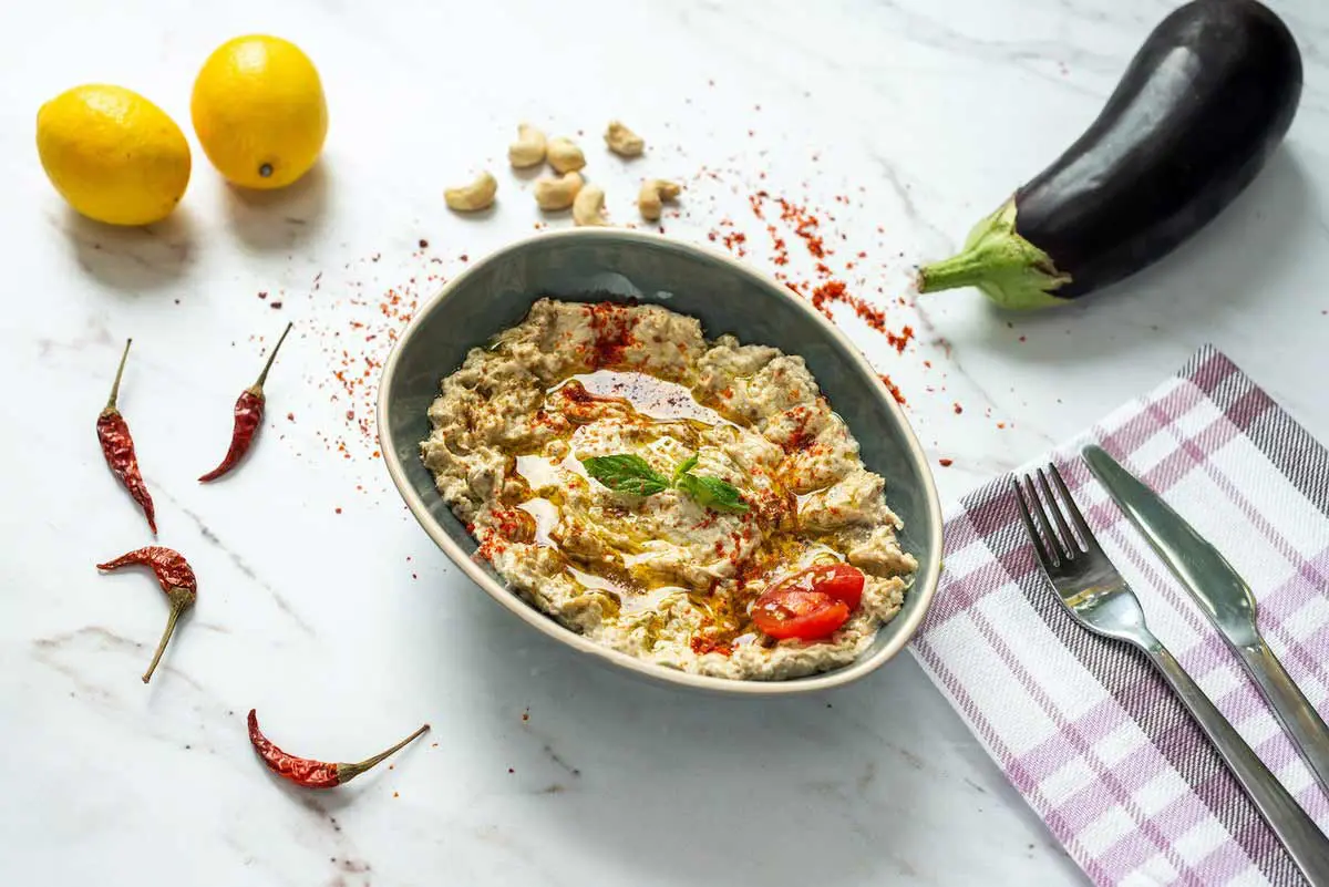 Mediterrane Vorspeise: Baba Ghanoush aus gerösteter Aubergine mit frischen Zutaten.