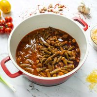 Okra Draufsicht auf einen herzhaften Okra-Eintopf mit Reis und frischen Zutaten auf einem hellen Tisch.
