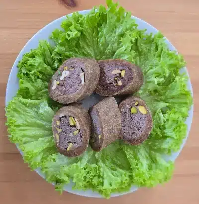 Kibbeh Mabrouma - kunstvoll geformtes Fingerfood aus Rindfleisch, Bulgur und Pistazien, perfekt für besondere Anlässe.