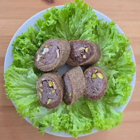 Kibbeh Mabrouma - kunstvoll geformtes Fingerfood aus Rindfleisch, Bulgur und Pistazien, perfekt für besondere Anlässe.