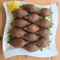 Kubba mit Fleisch – traditionelle syrische Vorspeise, serviert auf Salat mit Zitronenscheiben.