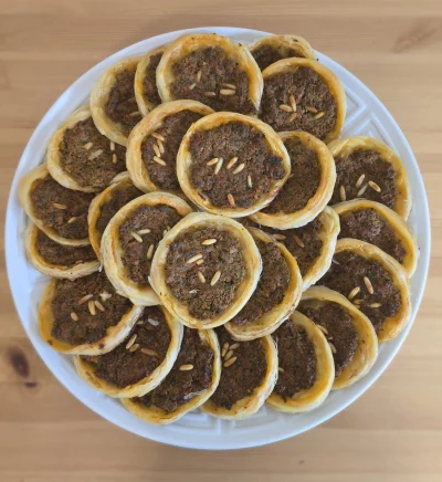 Frisch gebackenes Hackfleisch Eish albulbil– dünner Teig belegt mit würzigem Hackfleisch, Petersilie und Tomaten, angerichtet auf grünem Salat.