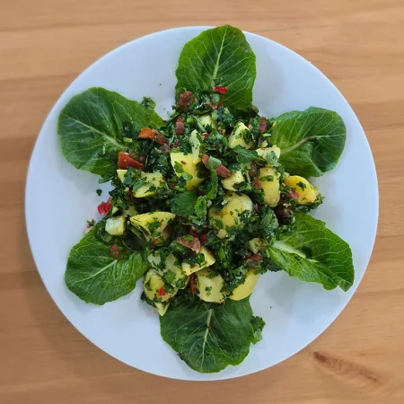 Arabisches Kartoffelsalat – Vorspeise mit Kartoffeln, Petersilie, Tomaten. Catering Berlin auf einem weißen Teller.