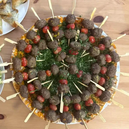 Orientalische Kebab-Spieße mit Bulgur, Pistazien und Gewürzen, serviert auf einem runden Teller.